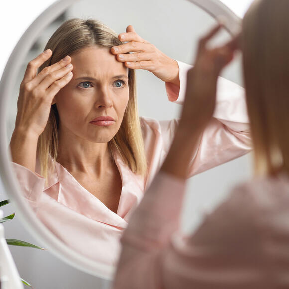 woman looking at her skin in the mirror